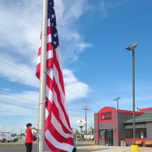 Two Brothers Cafe, young boy raising American Flag in front of restaurant